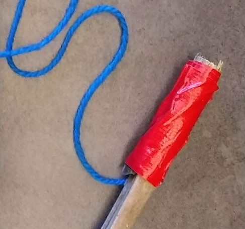 bamboo stick with blue string taped to one end with red tape