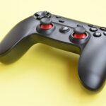 Modern black video game controller on yellow background. Online video game players community concept